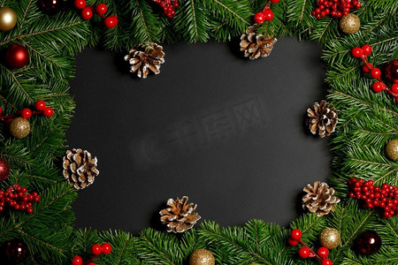 圣诞节在黑色背景的树枝边界框架与复制空间，小玩意儿，冬青浆果，松果圣诞节边界黑色背景