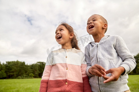 童年、休闲和人的概念-快乐微笑的小男孩和女孩在公园里。公园里快乐的小男孩和小女孩