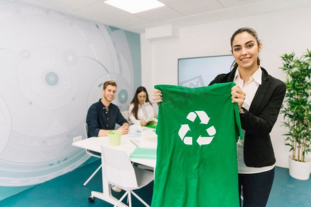 肖像快乐的年轻女商人显示绿色t恤与回收图标
