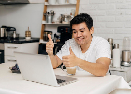 疫情期间男性在家视频通话笔记本电脑时竖起大拇指
