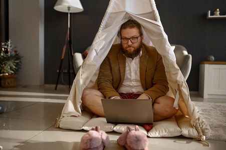 快乐的商人工作的笔记本电脑在家帐篷帐篷。快乐的男人放松，周末工作。快乐的商人工作笔记本电脑在家庭帐篷