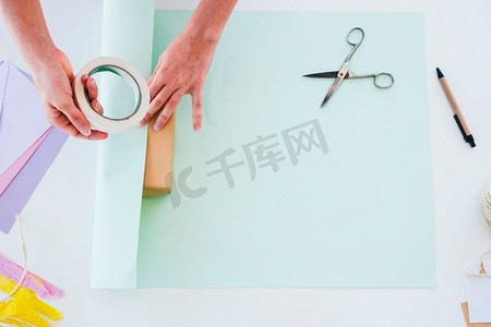 书桌纸摄影照片_俯视图妇女的手粘纸礼品盒白色桌子