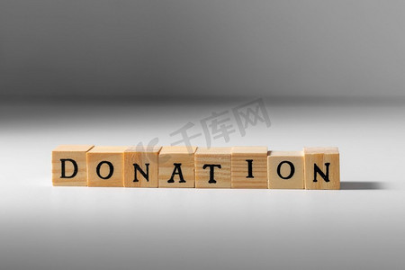慈善和财政援助概念—木制玩具块特写与捐赠词。木制玩具块捐赠字