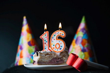 16号生日点燃蜡烛片蛋糕与党帽党喇叭吹