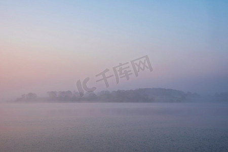 水库蓝色摄影照片_在水库湖上的春天日出的史诗风景图像与黎明的光辉散布在水与低雾添加大气