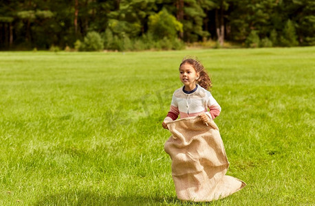 童年、休闲和人的概念-快乐的小女孩在公园里玩跳包游戏。快乐的小女孩在公园里玩跳包游戏