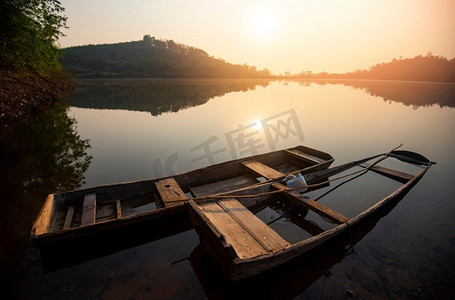 日出河，与阳光的冬天早晨在河上有山小山背景和木船，渔船