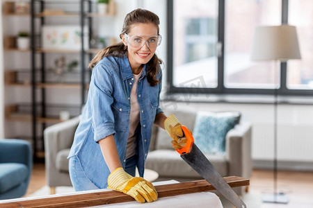 修理，DIY和家庭改善概念—愉快的微笑的妇女护目镜与锯木板。妇女与锯木板在家里