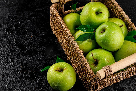 篮子里的新鲜青苹果。在黑色背景上。高质量的照片。篮子里的新鲜青苹果。