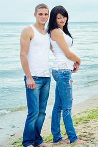 男孩和一个女孩在牛仔裤和白色T恤在海边