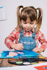 水粉展板摄影照片_可爱的女孩画与蓝色水粉木桌子