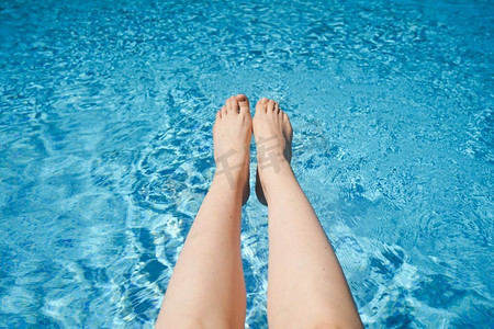 白色女人的腿顶着青绿色的池水