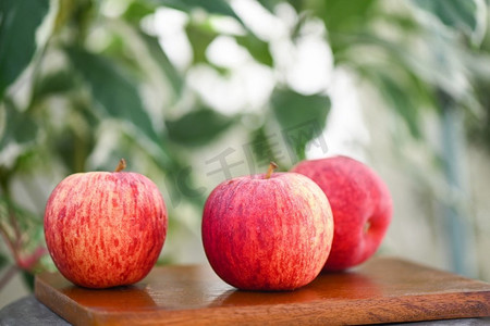 成熟的苹果摄影照片_在木桌上的苹果果自然绿色背景，成熟的红苹果