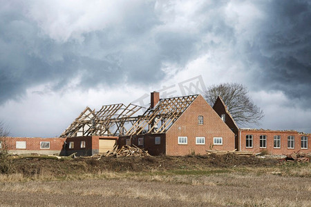 房屋被暴风雨损坏，屋顶在多云的天空下被摧毁