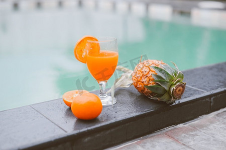 汁水摄影照片_泳池边有一杯果汁，泳池边有橙汁和菠萝