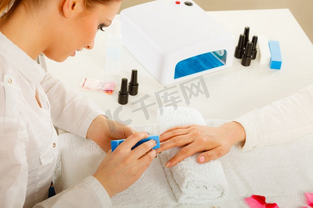 女人的手放在毛巾上，美容师锉指甲。美容养生水疗护理，美甲概念。妇女得到美甲做文件指甲