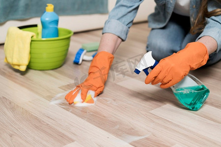 打扫房子摄影照片_一个戴着橡胶手套的女人在打扫地板
