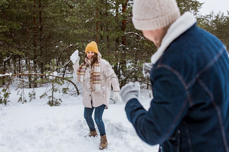 人，季节和休闲的概念—愉快的夫妇打雪球在冬季公园。愉快的夫妇玩雪球在冬季公园