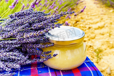 与蜂蜜的罐对新鲜熏衣草领域背景。法国普罗旺斯一罐蜂蜜和熏衣草花。