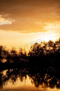 橙色浪漫摄影照片_橙色日落在河上与树的剪影