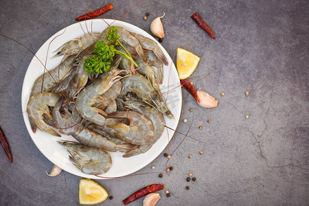 在白色盘子的生虾，新鲜的虾虾用香料在黑暗背景的柠檬烹饪在海鲜餐馆