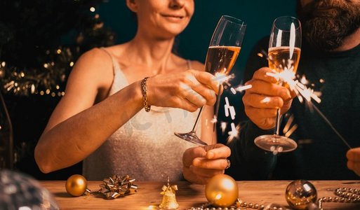 幸福的情侣手持汽水和香槟酒杯参加新年晚会