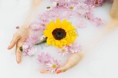 关闭妇女的手与黄色粉红色的花漂浮的水