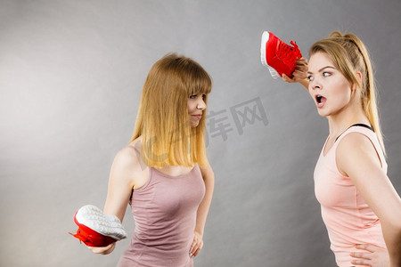 两个好斗的女人用鞋吵架，互相生气。女性暴力观念两个侵略性的妇女战斗使用鞋