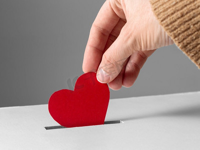 慈善、爱与情人节概念—近距离把红心放进募捐箱。’手把红心放进募捐箱