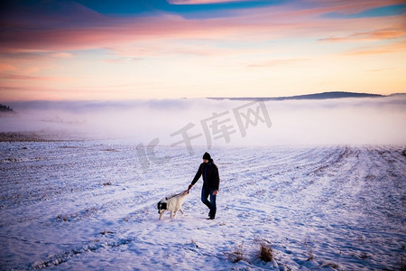 人与他的狗在雾冬天风景在日落