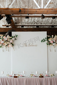 宴会厅摄影照片_餐厅宴会厅的新婚夫妇主席团用蜡烛和绿色植物装饰，紫藤从天花板上垂下来