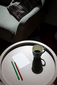 咖啡杯和空白卡在桌子上在严酷的阳光