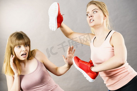 侵略妇女有争吵打架用鞋，女性朋友害怕。暴力概念女人与鞋搏斗