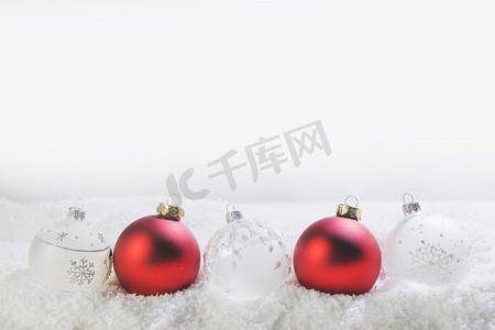 白色雪地背景上的红白相间的圣诞球，带有复制空间。雪地上的圣诞球
