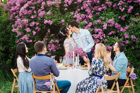 在春天的花园里，新娘和新郎和朋友们坐在婚桌上