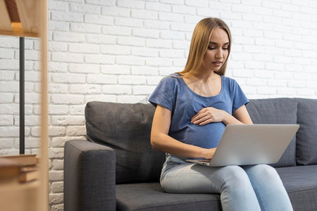 怀孕的女商人沙发工作与笔记本电脑