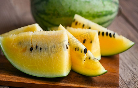 黄色西瓜摄影照片_特写镜头甜的西瓜片片新鲜的西瓜热带夏天水果，黄色西瓜片在木背景