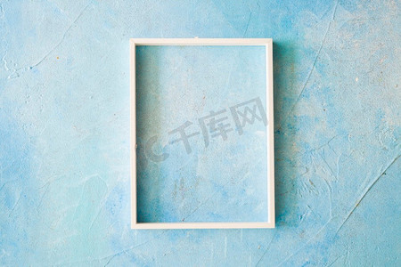 边框蓝色边框摄影照片_空框架与白色边框蓝色漆墙