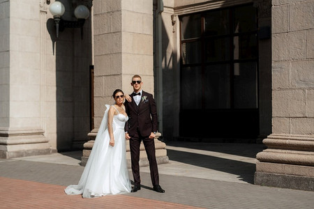 都市家庭摄影照片_在都市气氛中，身穿棕色西装的新郎和穿着白色裙子的新娘