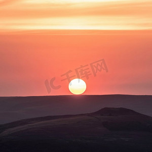 风景淡紫色摄影照片_令人惊叹的夏末日落风景图像日落亲吻地平线在山顶区，从Higger Tor观看