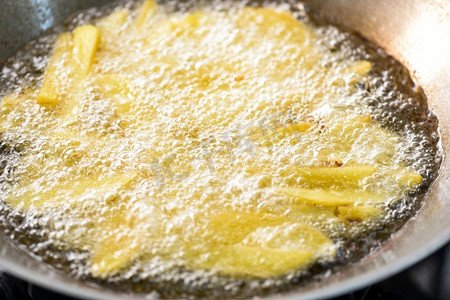 酸笋豆角摄影照片_炸薯条或用热油炸土豆做土豆角，把油炸土豆放在平底锅里