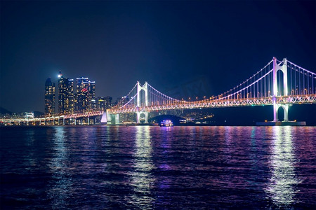 光岸大桥和摩天大楼在夜色中灯火通明。韩国釜山。光岸大桥和夜间的摩天大楼。韩国釜山