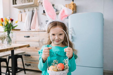 女孩兔子耳朵举行篮子与复活节彩蛋