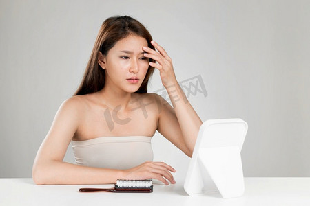 照镜子的年轻热心亚洲女性的画像担心她脸上的疙瘩.文胸美女