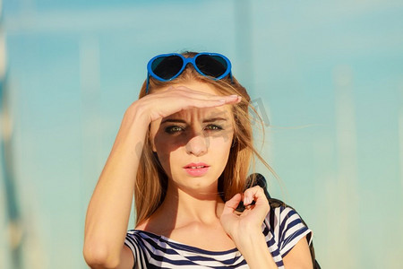 夏季放松概念肖像女孩与蓝色心形太阳镜享受夏季微风室外在码头