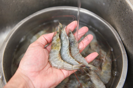 生虾手洗虾在水槽的碗里，新鲜的虾虾在厨房里煮海鲜食品