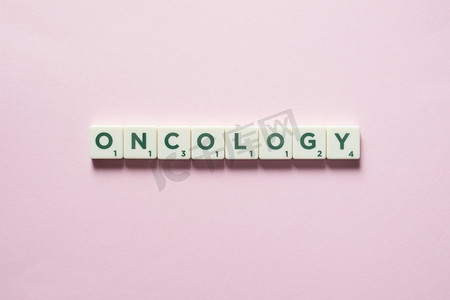 肿瘤患者摄影照片_肿瘤词形成的拼字砖粉红色背景。癌症与身体健康意识肿瘤学是由瓷砖形成的。