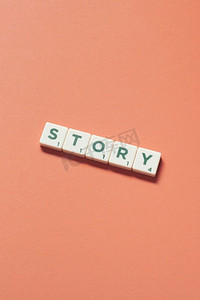 轻扫摄影照片_故事词形成的拼字瓷砖橙色背景。创意网页设计在粉彩的颜色。故事形成的拼字游戏瓷砖橙色背景。