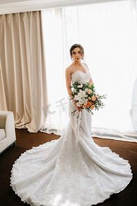 新娘在一个白色的礼服与花束在酒店房间
