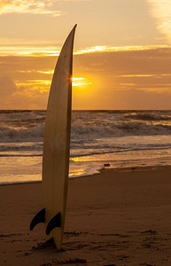 冲浪板站在沙滩上在日落或日出